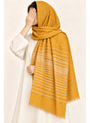Mustard Turkish lawn scarf with white stripes and fringed edges by Hijab ul Hareem, worn as a hijab